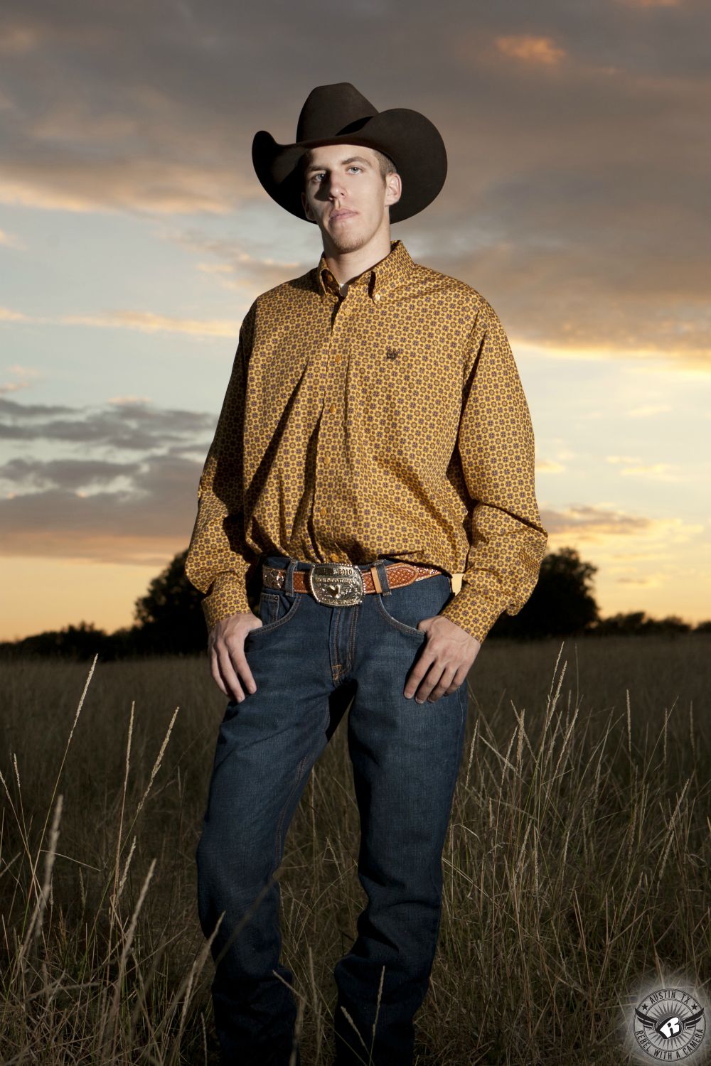 Country senior portraits Central Texas of high school senior boy in cowboy hat, yellow shirt, and jeans.